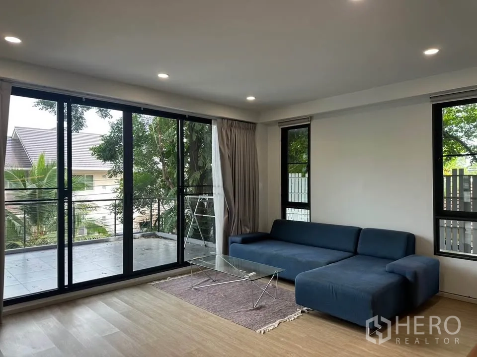 Detached House for sale in Watthana, Bangkok - Second-floor lounge with sofa opening to a balcony and tree views.
