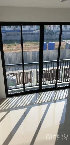 Factory for rent in Lam Luk Ka, Pathum Thani - Sliding glass doors opening to a balcony overlooking the gated frontage.