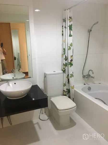 Condominium for rent or sale in Watthana, Bangkok - Bright bathroom with bathtub, handheld shower, vessel sink and white tiles.