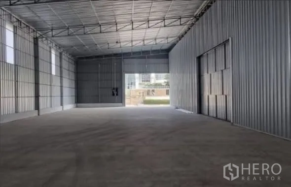 Warehouse for rent in Bang Kapi, Bangkok - Open warehouse interior showing metal roof structure and large entry doors.