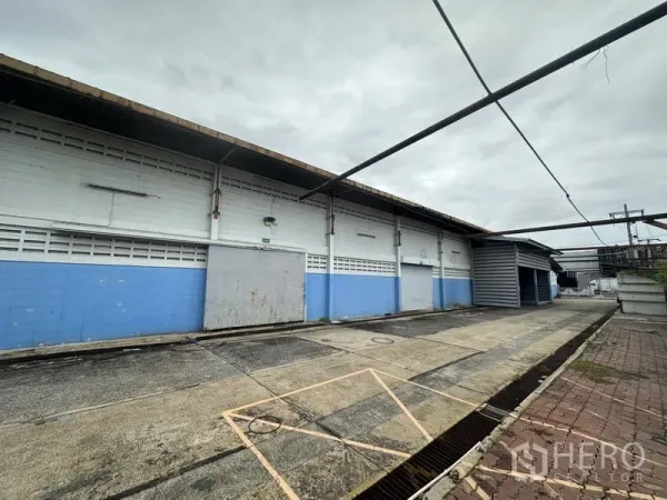 โรงงาน ขายในKhlong Luang, Pathum Thani - ผนังภายนอกโกดังยาว พร้อมประตูโหลดและทางเดินบริการมีหลังคา