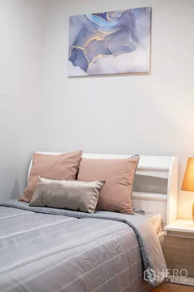 公寓 出租或出售在Khlong Toei, Bangkok - 温馨卧室一角，柔软床品、床头灯与抽象画。