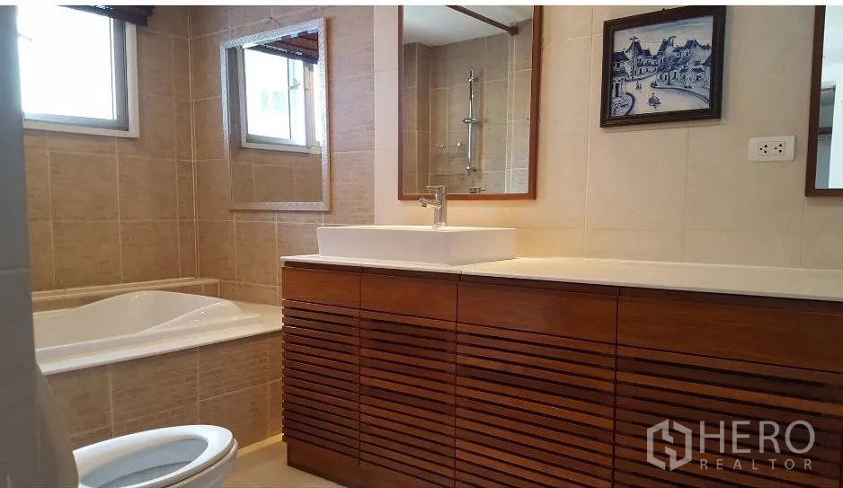 Condominium for rent in Watthana, Bangkok - Tiled bathroom featuring a bathtub, vessel sink, wide wooden vanity, and mirror.