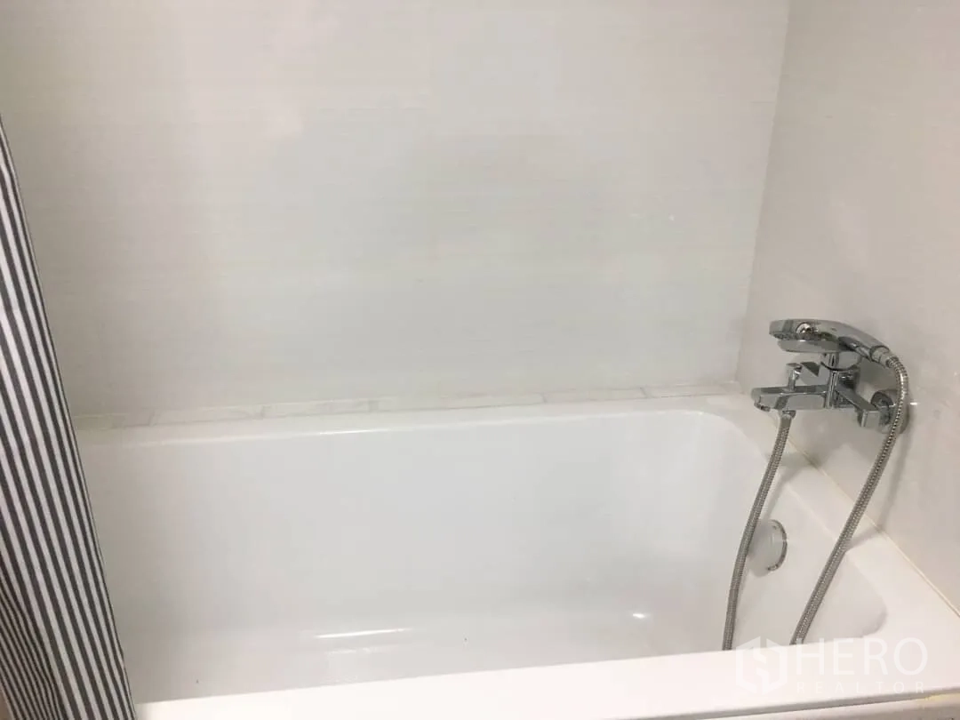 Condominium for rent in Watthana, Bangkok - Bathroom with clean white bathtub and handheld shower against tiled wall