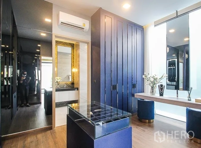 Detached House for rent or sale in Prawet, Bangkok - Walk-in closet with blue cabinetry, dressing table and large window.