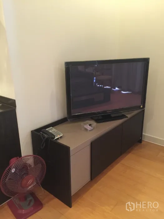 Condominium for rent in Bang Kho Laem, Bangkok - Living area with flat-screen TV on a media console and a portable fan.