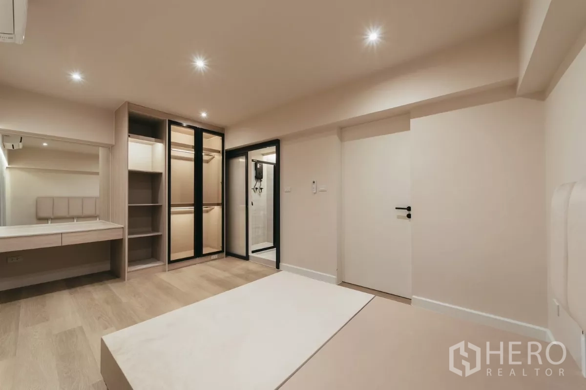 联排别墅 出租在Watthana, Bangkok - 套房卧室，内置衣柜、梳妆台与卫浴入口。