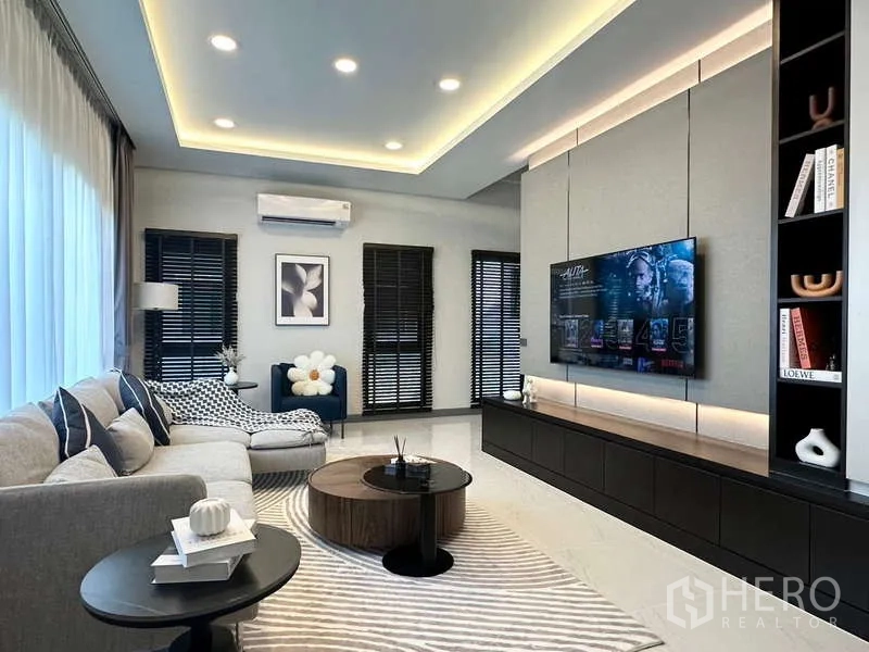 บ้าน ให้เช่าในBang Phli, Samut Prakan - ห้องนั่งเล่นหลัก ผนังทีวีดีไซน์ ไฟฝ้าซ่อน และโซฟาเข้ามุม