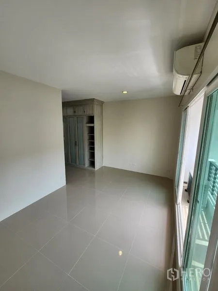 Townhouse for rent in Wang Thonglang, Bangkok - Bedroom with built-in wardrobe, air conditioning and access to a balcony.