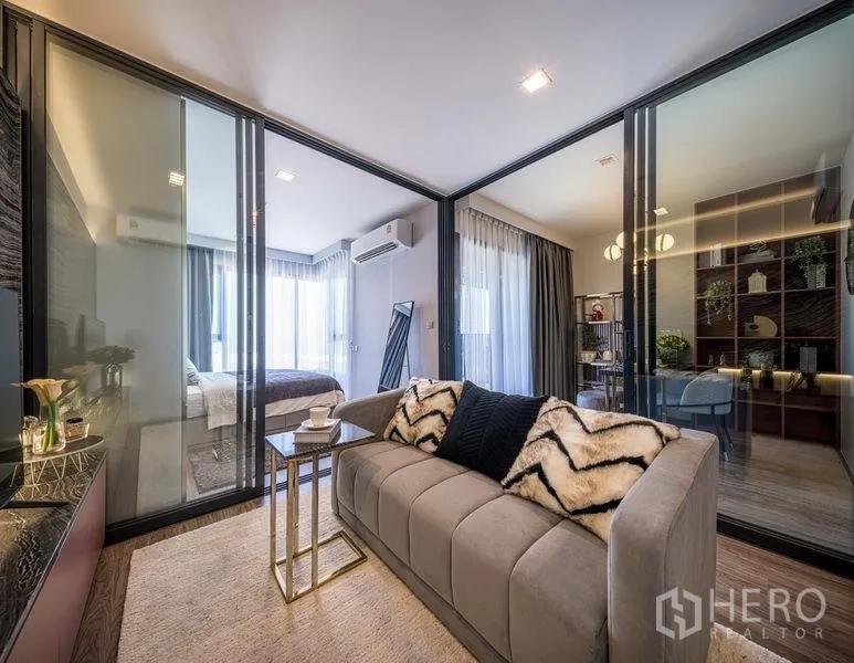 Condominium for sale in Chatuchak, Bangkok - Living room framed by glass-walled bedroom and study, with floor-to-ceiling curtains and abundant light.