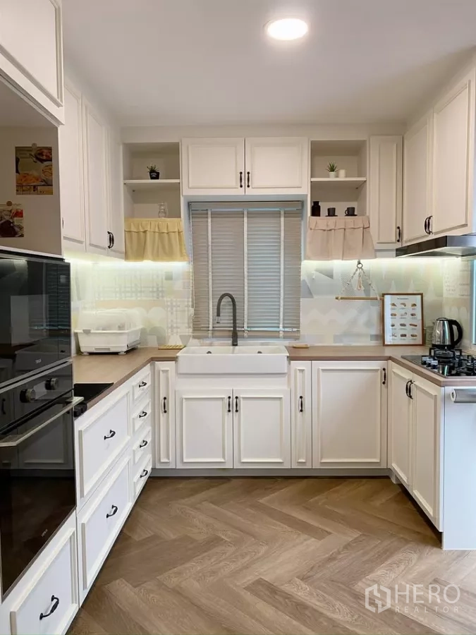 独立式住宅 出售在Sai Mai, Bangkok - U形厨房，农舍式水槽、白色橱柜与橱下照明。