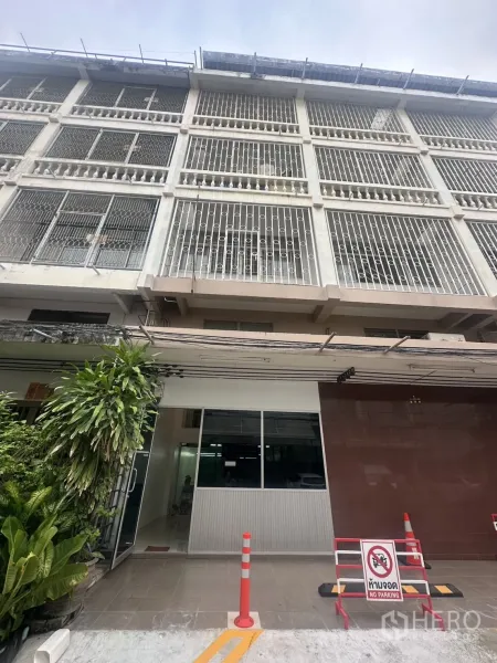 สำนักงาน ให้เช่าในKhlong Toei, Bangkok - อาคารสำนักงานหลายชั้นด้านหน้าเหล็กดัด ทางเข้าเป็นกระจก มีต้นไม้และป้ายห้ามจอด.