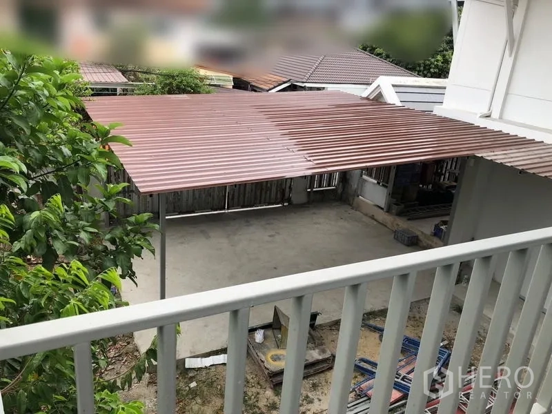 Detached House for rent - Covered concrete carport with a metal roof viewed from the balcony and a fenced yard below.