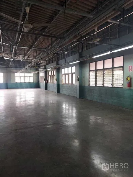 Warehouse for rent in Min Buri, Bangkok - Spacious warehouse interior with polished concrete floor, high ceilings, steel trusses and side windows with strip lighting.