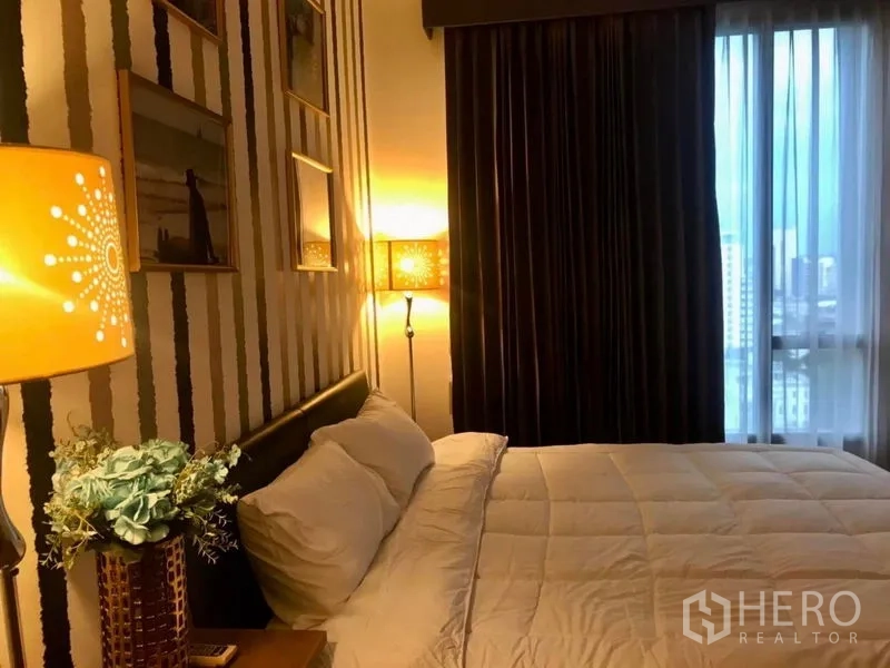 公寓 出租在Watthana, Bangkok - 温馨卧室，条纹墙面、床头灯和大窗户。