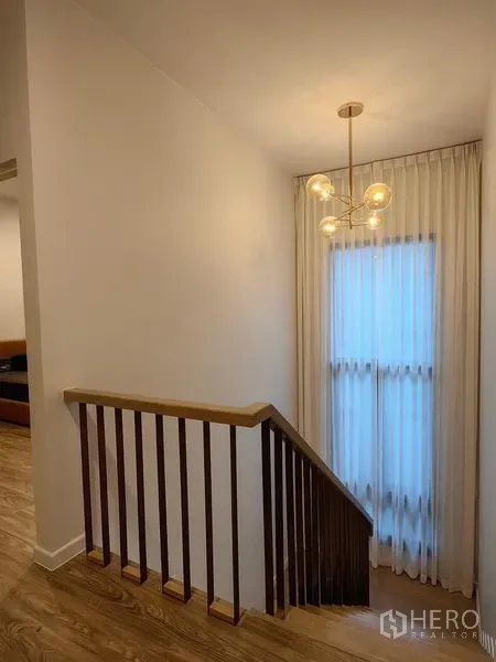 独立式住宅 出租在Bang Kapi, Bangkok - 木质楼梯与细条扶手，旁有吊灯和落地窗