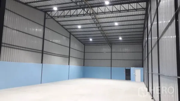 货栈 出租在Khlong Luang, Pathum Thani - 仓库开放式地面空间，顶装高棚灯，蓝色下半墙，设有大推拉门及侧门通往卫生间/办公区。