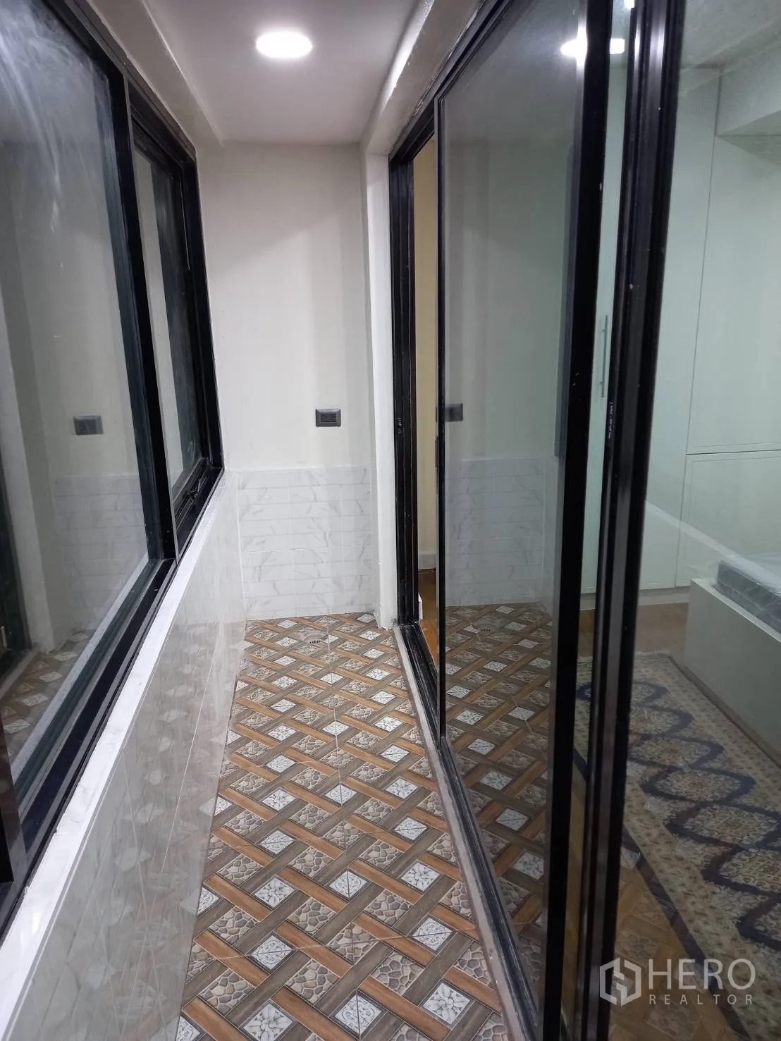 公寓 出租在Khlong Toei, Bangkok - 封闭式阳台，几何花纹地砖与黑框推拉玻璃窗。