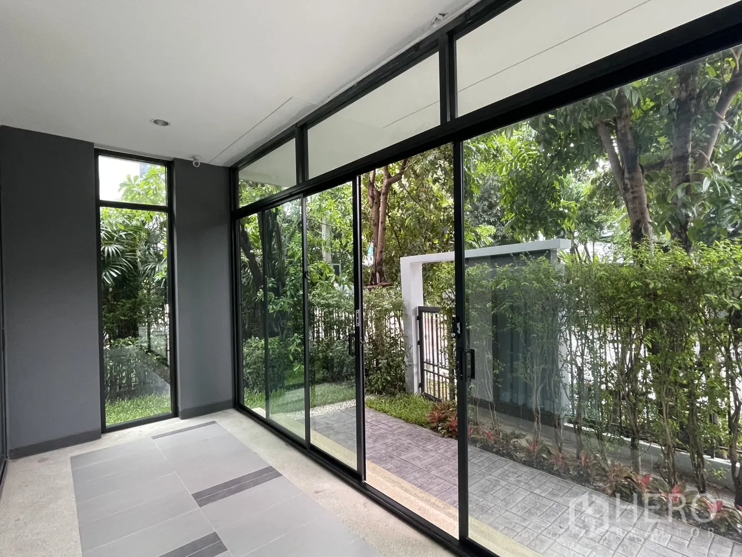 Detached House for rent in Bang Kapi, Bangkok - Enclosed terrace sunroom with full-height sliding glass overlooking greenery.