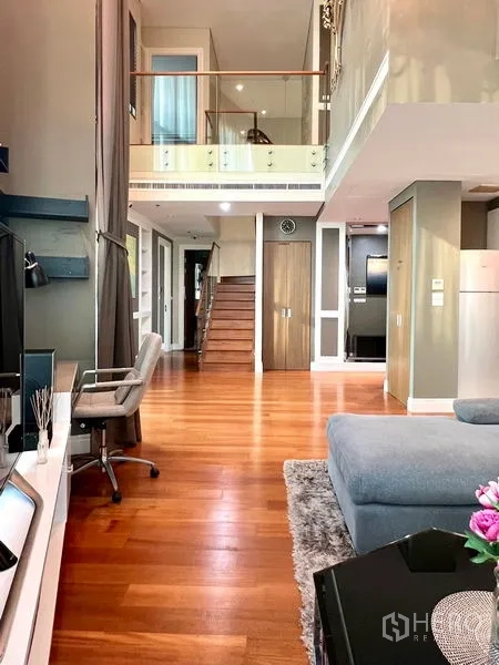 คอนโด ให้เช่าในKhlong Toei, Bangkok - มุมมองไปยังบันไดจากห้องนั่งเล่น พร้อมชั้นวางทีวีและเพดานสูง