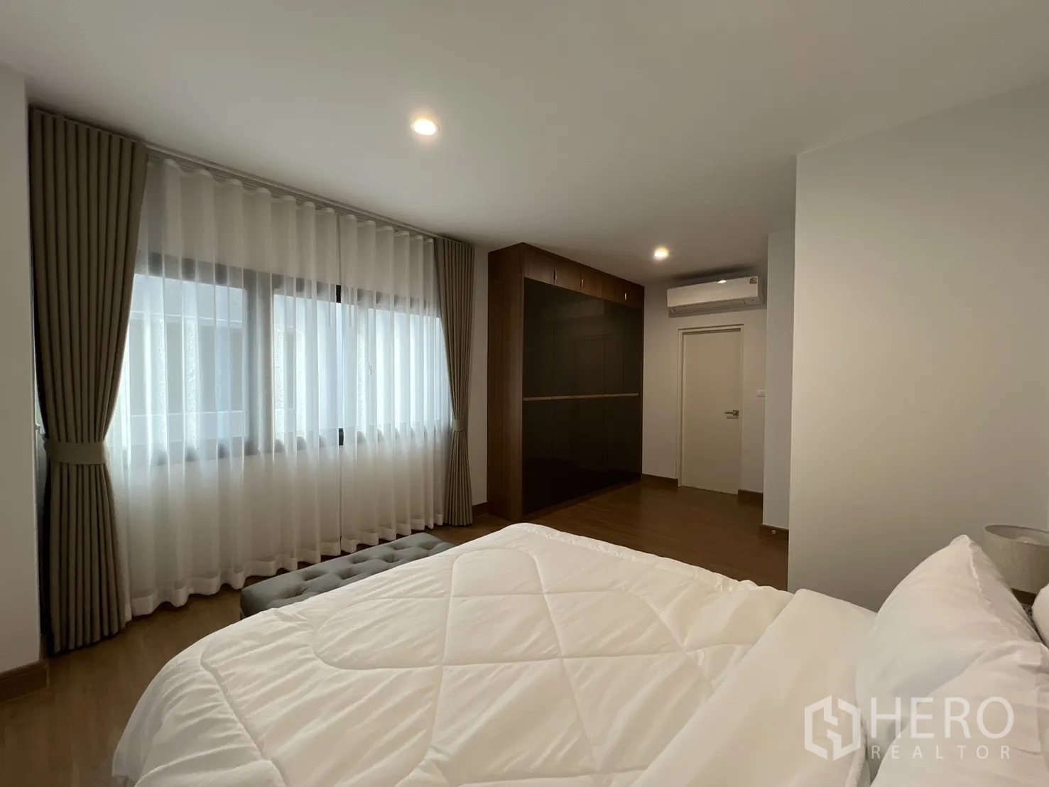 Detached House for rent in Prawet, Bangkok - Large bedroom with wall of glossy wardrobes and wide windows.