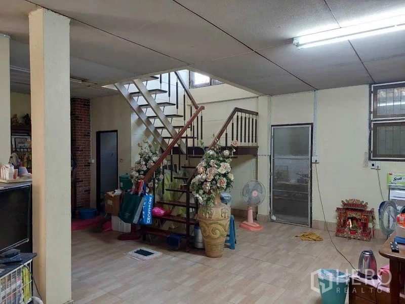 Townhouse for sale - Ground-floor living area with open staircase, tiled floors, fluorescent lighting, and side windows.