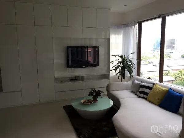 คอนโด ให้เช่าในKhlong Toei, Bangkok - ห้องนั่งเล่นมีผนังบิวท์อินทีวี โซฟาตัวแอล ไม้ประดับ และหน้าต่างพาโนรามาวิวเมือง