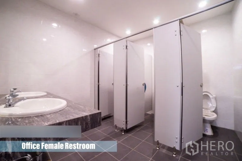 Home Office for rent in Khlong Toei, Bangkok - Clean restroom featuring multiple toilet stalls and double sinks on a stone countertop.