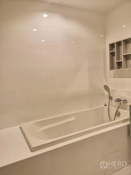 公寓 出租在Watthana, Bangkok - 内置式白色浴缸，带手持花洒与壁龛置物架。