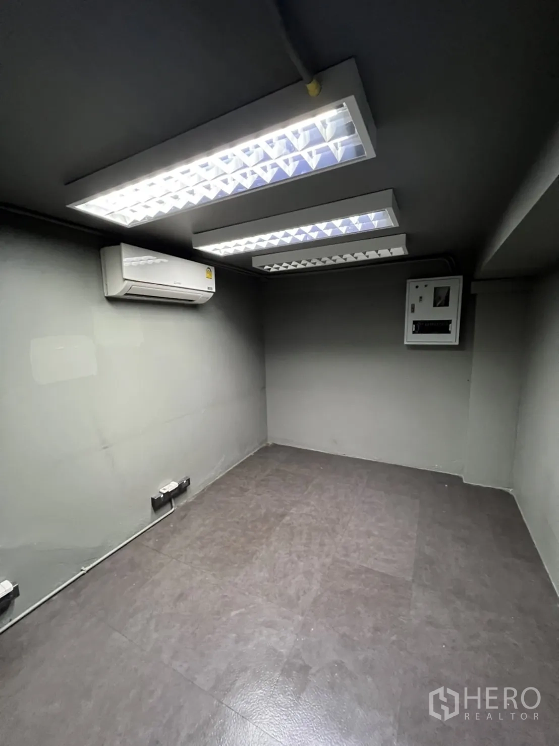 店屋 出租在Phra Khanong, Bangkok - 小型办公室，吊顶日光灯、分体空调与配电箱，灰色墙面