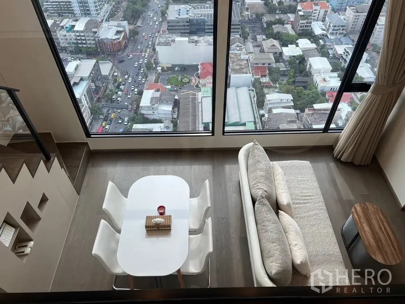 公寓 出租在Ratchathewi, Bangkok - 自上而下俯拍，餐桌与沙发靠大幅观景窗。