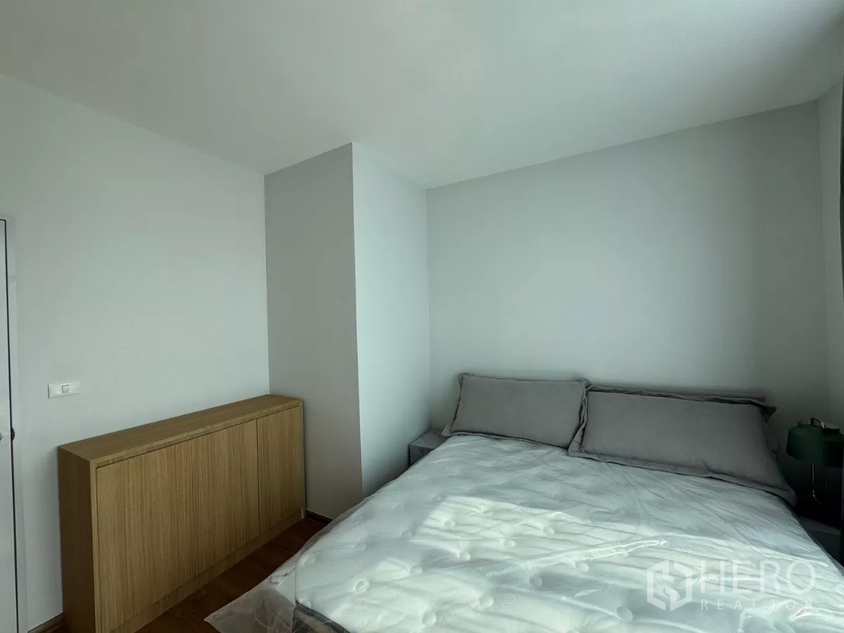 ทาวน์เฮาส์ ให้เช่าในBang Phli, Samut Prakan - อีกมุมของห้องนอนใหญ่ เห็นเตียงและตู้ล่างไม้ใกล้หน้าต่าง