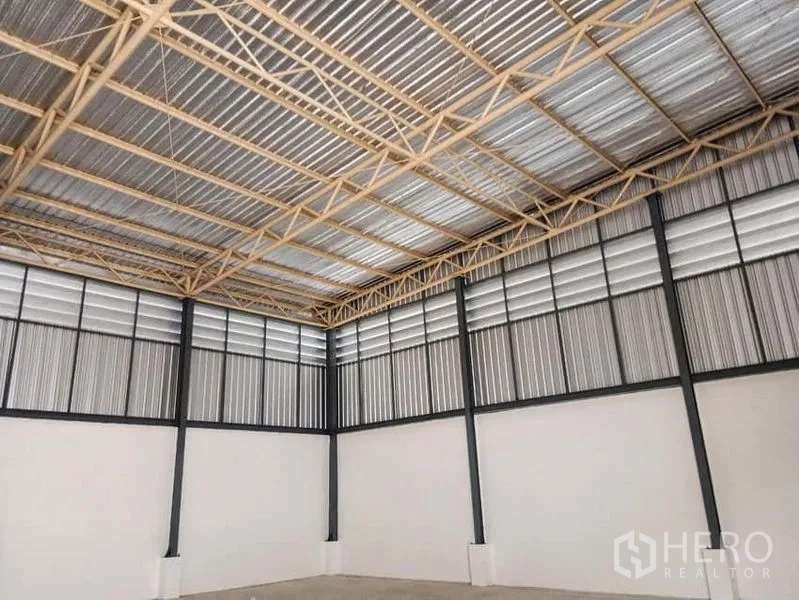 Warehouse for rent in Suan Luang, Bangkok - High-ceiling steel truss roof and louvered wall panels for airflow inside the empty warehouse.