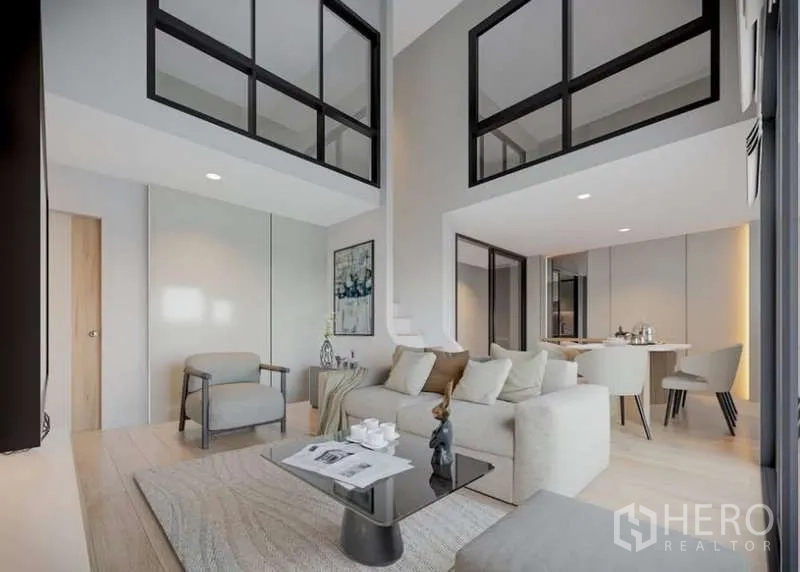 Condominium for rent in Huai Khwang, Bangkok - Open-plan living and dining area with loft glazing and light wood floors.