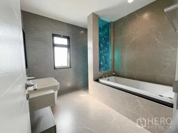 Detached House for sale in Mueang Nonthaburi, Nonthaburi - Contemporary bathroom with built-in soaking tub, twin basins, and a window.