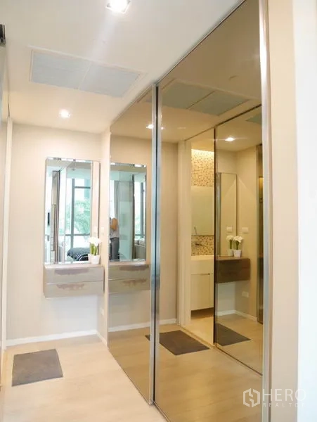 Condominium for rent or sale in Watthana, Bangkok - Walk-through dressing area with mirrored wardrobes leading to the bathroom vanity.