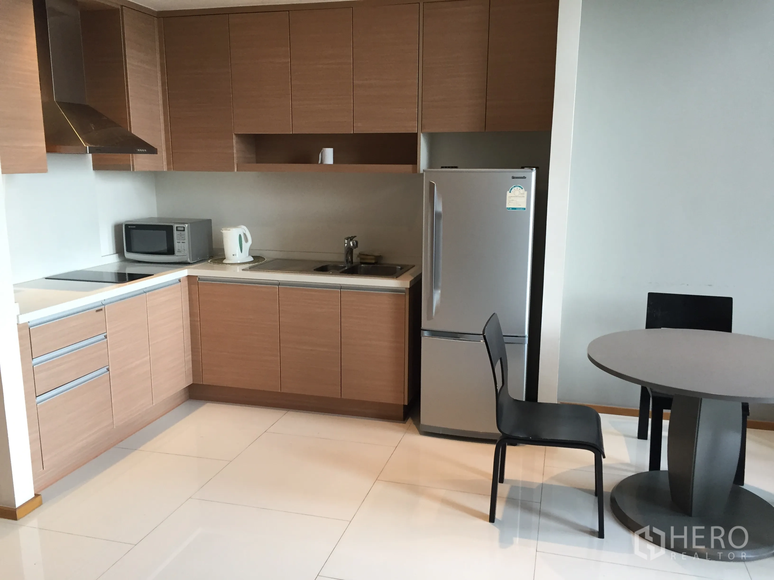 คอนโด ให้เช่าในKhlong Toei, Bangkok - ครัวรูปตัวแอลตู้ไม้ เตา ไมโครเวฟ และโต๊ะทานอาหารขนาดเล็ก