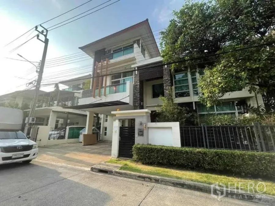 บ้าน ให้เช่าหรือขายในKhan Na Yao, Bangkok - มุมมองหน้าบ้าน เห็นประตูรั้ว ทางรถเข้าบ้าน โรงจอดรถ และแนวต้นไม้ในทำเลพรีเมียม