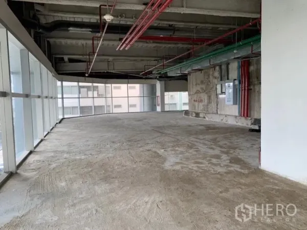 พื้นที่ขายปลีก ให้เช่า - พื้นที่ค้าปลีกมุมอาคาร กระจกโอบรอบ ท่อระบบงานวิศวกรรมแบบเปิด และพื้นคอนกรีตดิบ