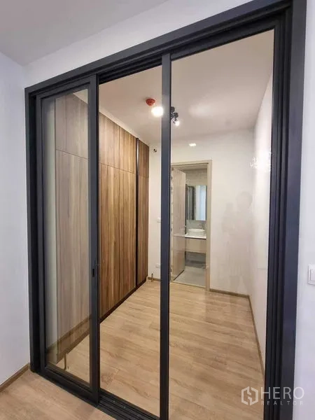 公寓 出租在Ratchathewi, Bangkok - 玻璃推拉门通向走廊，内设木质衣柜与浴室。