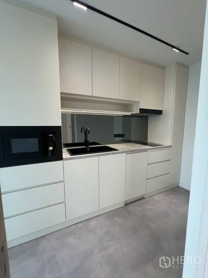 Townhouse for rent in Prawet, Bangkok - Full view of modern kitchen with ample storage and grey floor.