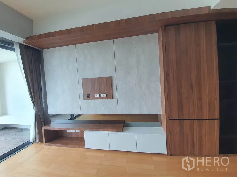 Condominium for rent in Yan Nawa, Bangkok - Custom built-in TV cabinet and storage beside floor-to-ceiling balcony glass doors.