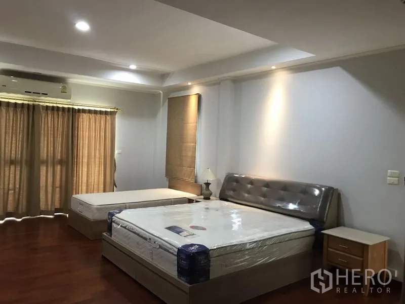 独立式住宅 出租在Phra Khanong, Bangkok - 主卧空间宽敞，木地板、两张床、筒灯与遮光窗帘。