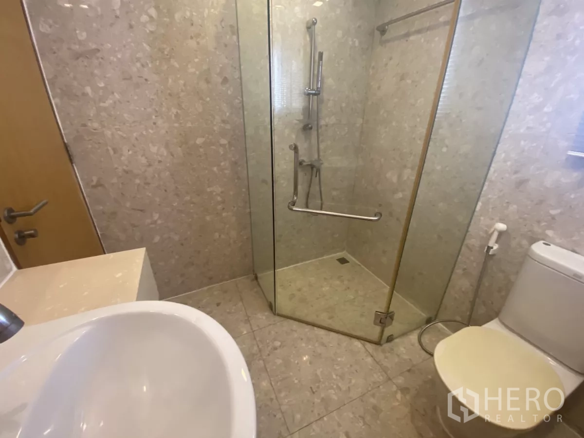 คอนโด ให้เช่าในWatthana, Bangkok - ภาพใกล้ของห้องอาบน้ำปูกระเบื้อง มีฝักบัวสายอ่อนและเรนชาวเวอร์ข้างโถสุขภัณฑ์