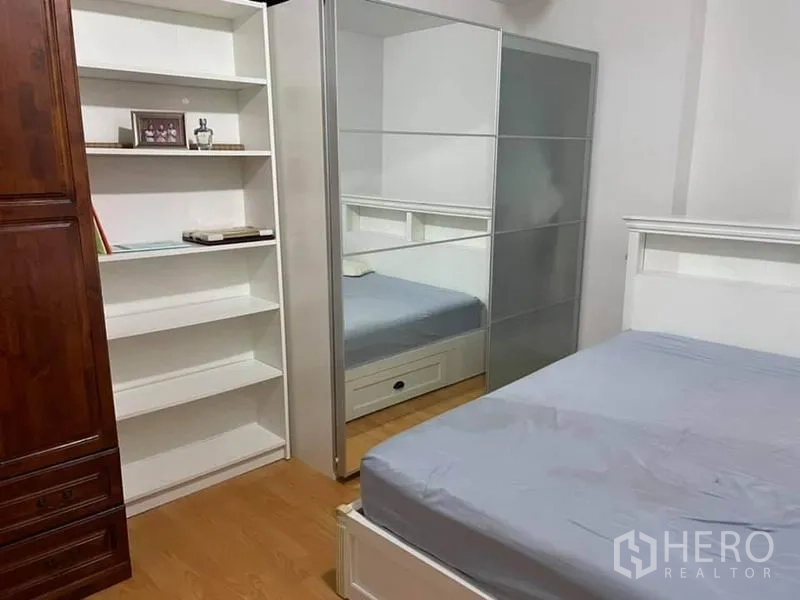 Condominium for rent or sale in Watthana, Bangkok - Second bedroom with built-in shelves, mirrored sliding wardrobe, and platform bed.