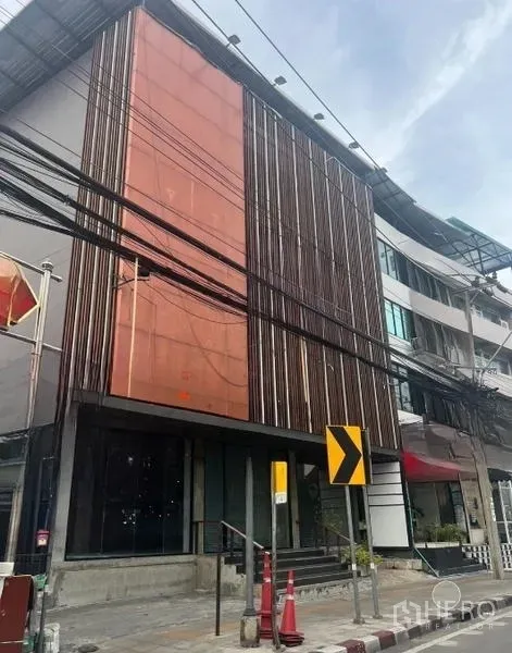 店屋 出租 - 同栋建筑的侧角度，橙色覆板与高挑格栅，台阶入口与玻璃门面。