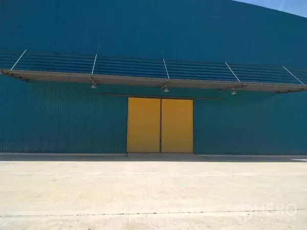 工厂 出租在Mueang Samut Prakan, Samut Prakan - 厂房外立面为青绿色金属板，配黄色推拉大门、雨棚与混凝土装卸坪。