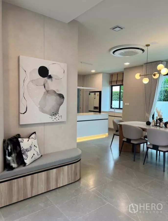 Detached House for rent in Samut Prakan - Open-plan kitchen and dining space with an island, built-in bench nook, large windows and tiled floors.