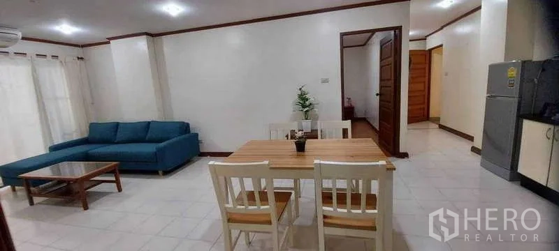 คอนโด ให้เช่าในKhlong Toei, Bangkok - พื้นที่ทานอาหารและนั่งเล่น โต๊ะไม้ 4 ที่นั่ง โซฟาสีฟ้า พื้นกระเบื้อง และผ้าม่านโปร่ง