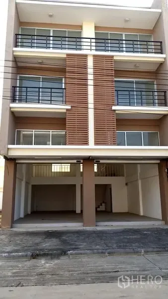 Office Space for sale in Khlong Luang, Pathum Thani - Front elevation of a four‑storey office building showing open double‑bay carport, glass‑railed balconies and louvered facade.